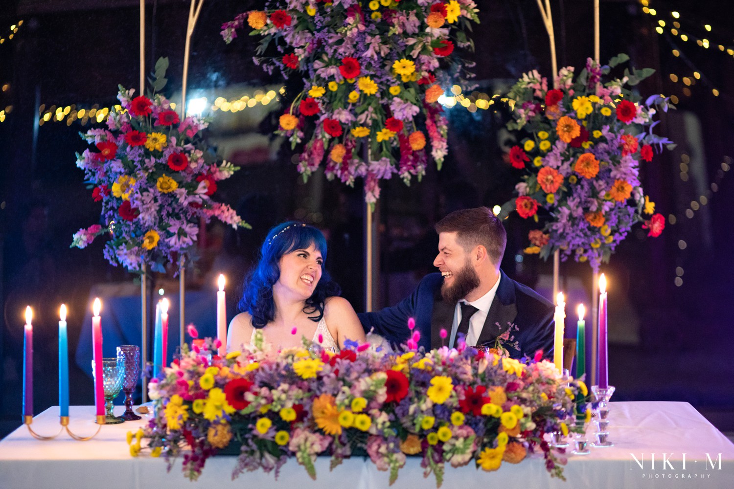 Bride and groom laughing together at their sweetheart table by candlelight at a Champagne Valley Drakensberg wedding