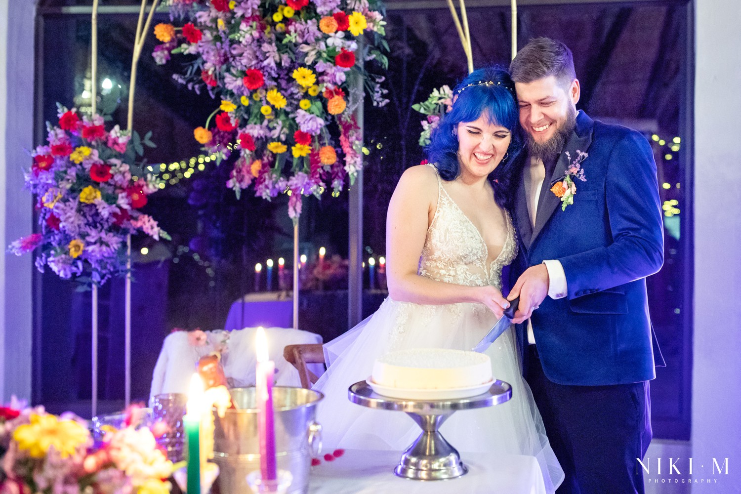 Bride and groom cutting their wedding cheese cake beneath the wildflower arch at a Champagne Valley Drakensberg wedding