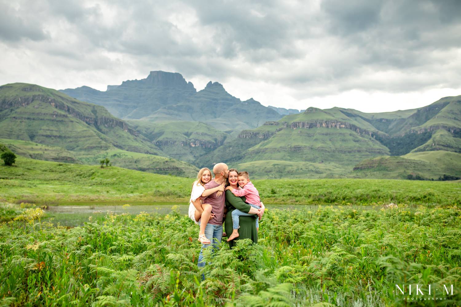 Family hugging in a fern field below Cathkin Peak during a Drakensberg family photoshoot at Monks Cowl Reserve