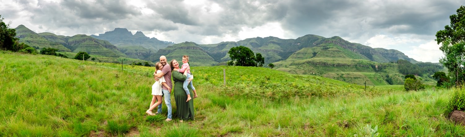 Panoramic view of a family at Monks Cowl with the Drakensberg mountain range and Cathkin Peak rising behind