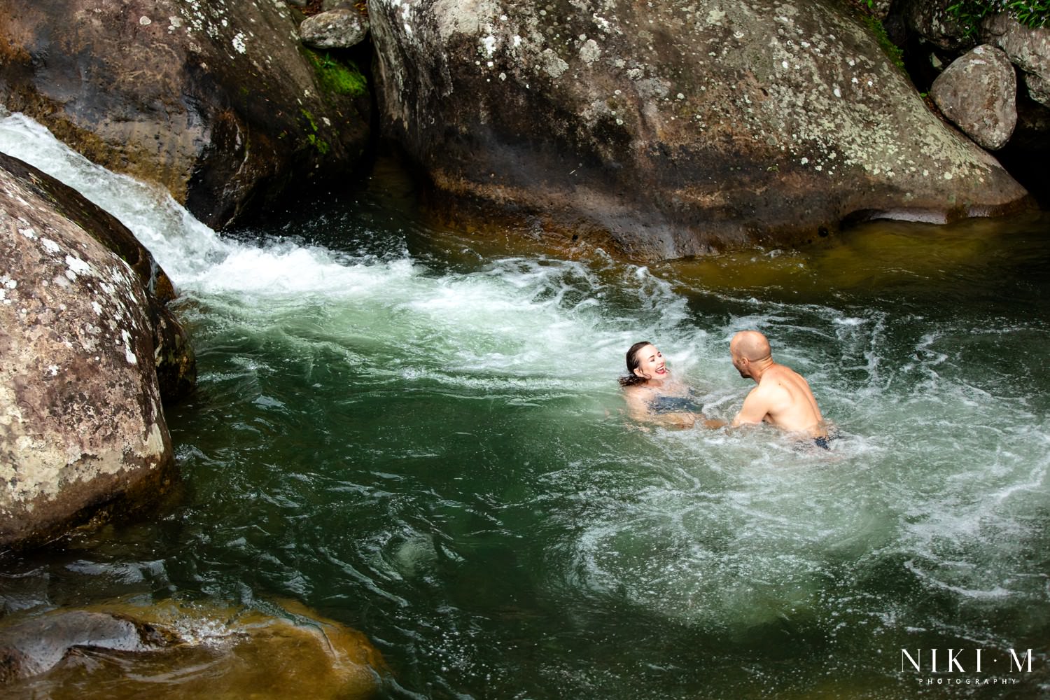 Sharne and Ryan laughing together in the swirling water of the Monks Cowl rock pools in the Central Drakensberg