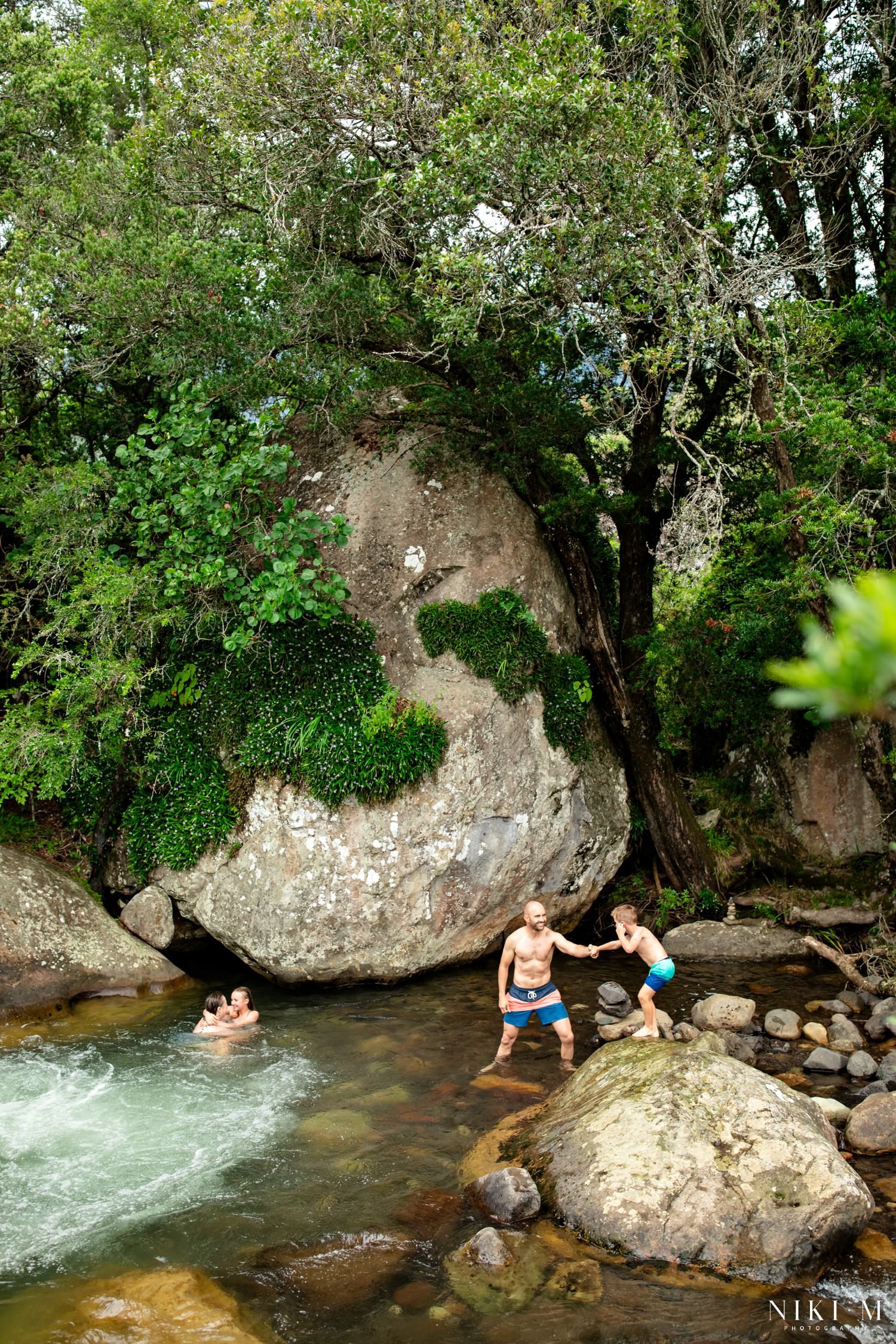 Family playing at the Monks Cowl rock pools surrounded by moss-covered boulders and indigenous Drakensberg forest