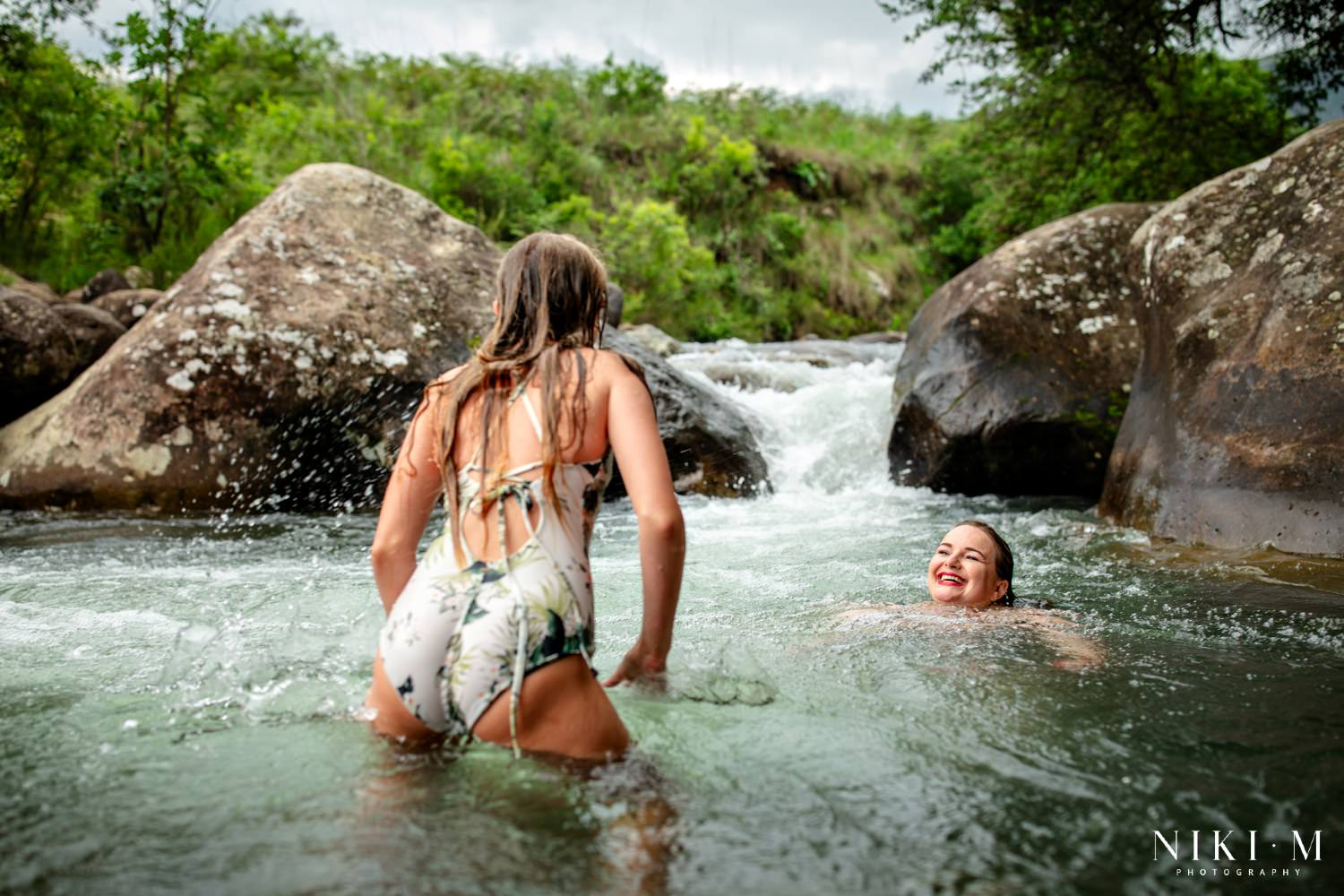Mother and daughter splashing in the Monks Cowl rock pools with the natural waterfall behind them